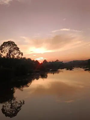 a river with the sun setting in the background at Kalidasa Tree House and Villa, Wayanad in Chekadi