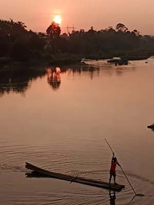 a man is standing on a boat in the water at Kalidasa Tree House and Villa, Wayanad in Chekadi