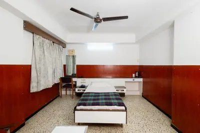 a hospital room with a bed and a ceiling fan at Hotel Srilakshmi in Coimbatore