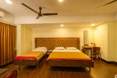 a bedroom with two beds and a ceiling fan at Hotel Srilakshmi in Coimbatore