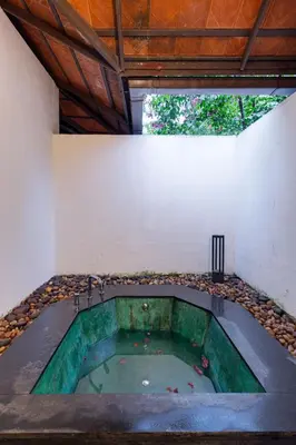 a hot tub in the middle of a building at Cranganor History Café & Riverside Château in Parūr