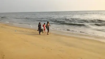 three women walking on the beach near the ocean at Kannur west beach homestay in Kannur