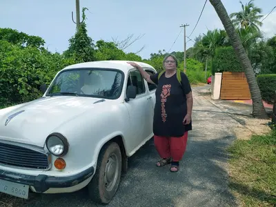 a woman standing next to a white car at Kannur west beach homestay in Kannur