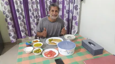 a man sitting at a table with a plate of food at Kannur west beach homestay in Kannur