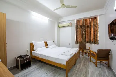 a bedroom with a bed and a desk and a chair at Sri Aarvee Hotels in Coimbatore
