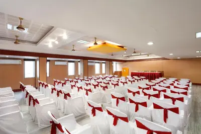 a room with rows of white chairs and red bows at Sri Aarvee Hotels in Coimbatore