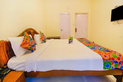a bedroom with a large white bed with colorful pillows at FabHotel Vinu Valley Resorts - Nr Ketti Valley View Point in Ooty