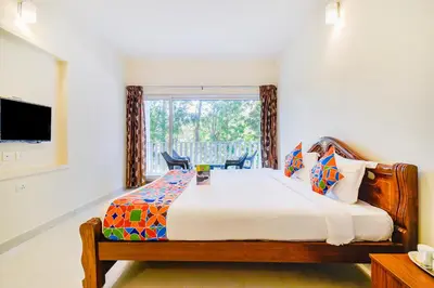 a bedroom with a large bed and a window at FabHotel Vinu Valley Resorts - Nr Ketti Valley View Point in Ooty