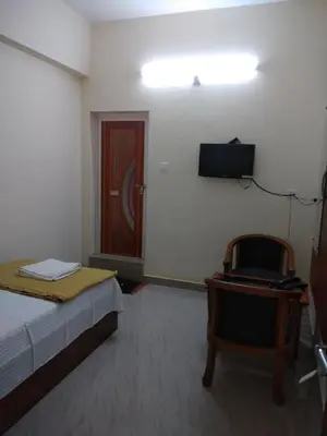 a bedroom with a bed and a chair and a door at Manjira Lodge in Guruvāyūr