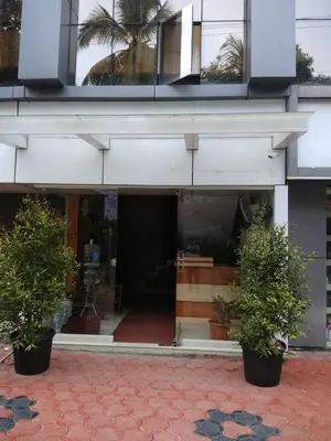 a building with two potted plants in front of it at Manjira Lodge in Guruvāyūr