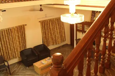 a room with a staircase with chairs and a chandelier at ShivalayaHomestay in Trichūr