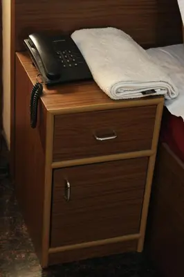 a phone sitting on top of a wooden table next to a bed at ShivalayaHomestay in Trichūr