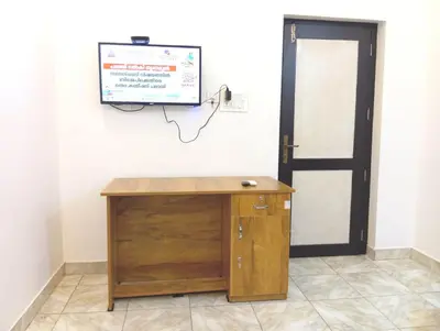 a room with a wooden desk and a television on a wall at Thekkumpuram Tourist Home in Malappuram
