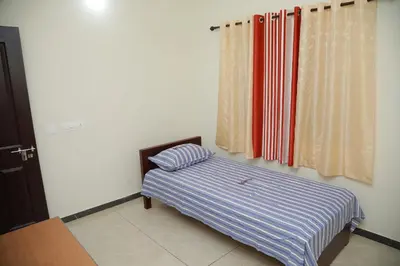 a bedroom with a bed with striped sheets and a window at Thekkumpuram Tourist Home in Malappuram