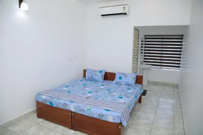 a bedroom with a bed with blue sheets and a window at Thekkumpuram Tourist Home in Malappuram