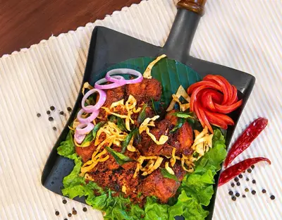a plate of food with noodles and vegetables on a table at Raindrops Resorts Wayanad in Sultan Bathery