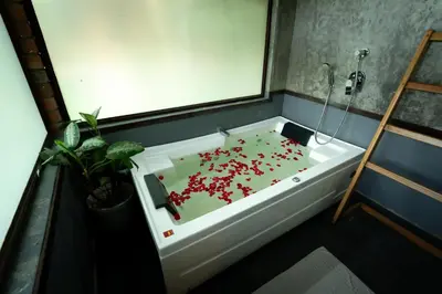 a bathroom with a bath tub with red flowers in it at Raindrops Resorts Wayanad in Sultan Bathery