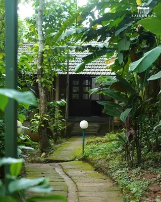 a stone path leading to a house in a garden at Raindrops Resorts Wayanad in Sultan Bathery