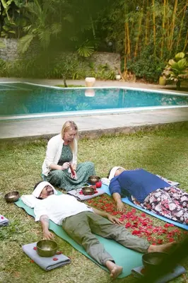 two people laying on the grass next to a pool at Raindrops Resorts Wayanad in Sultan Bathery