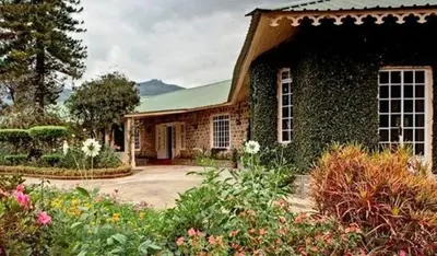 a brick house with a garden in front of it at Talayar Valley Bungalow in Idukki
