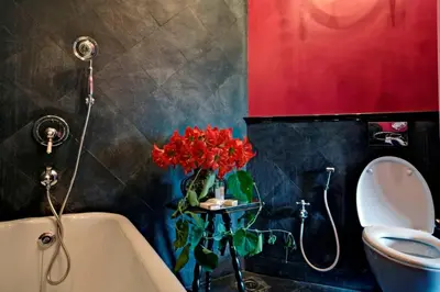 a bathroom with a vase of red flowers on a table next to a tub at Talayar Valley Bungalow in Idukki