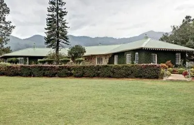 a green house with a green roof and a yard at Talayar Valley Bungalow in Idukki