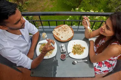 a man and a woman sitting at a table eating food at Mount n Mist in Ooty