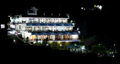 a large white building at night with lights at Mount n Mist in Ooty