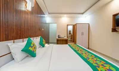 a bedroom with a large white bed with green pillows at Treebo Thoduvas Star Plaza Cochin Airport in Nedumbassery
