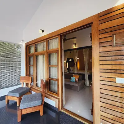 a living room with a chair and a bedroom at Riyavar Luxury Stay in Siddapur