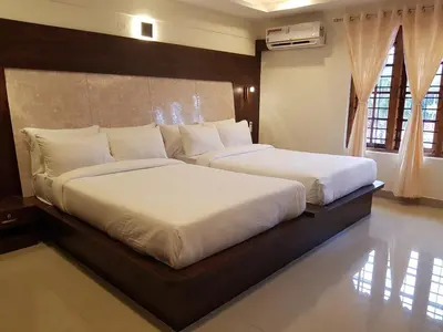 a bedroom with two beds with white sheets at Riyavar Luxury Stay in Siddapur