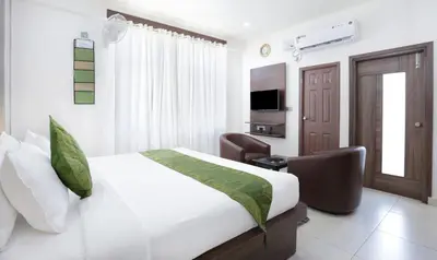 a bedroom with a bed and a chair and a television at Treebo Sandpipers Kushalnagar in Kushālnagar