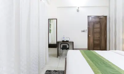 a white bedroom with a bed and a mirror at Treebo Sandpipers Kushalnagar in Kushālnagar