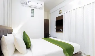 a bedroom with a bed with white and green pillows at Treebo Sandpipers Kushalnagar in Kushālnagar