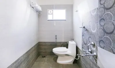 a bathroom with a toilet and a window at Treebo Sandpipers Kushalnagar in Kushālnagar