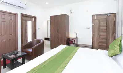 a bedroom with a large bed and a chair at Treebo Sandpipers Kushalnagar in Kushālnagar