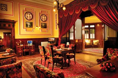 a living room with a table and chairs in a room at WelcomHeritage Fernhills Royal Palace in Ooty