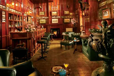 a room with a bar with green chairs and tables at WelcomHeritage Fernhills Royal Palace in Ooty