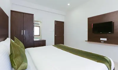 a bedroom with a bed with a tv on the wall at Treebo Hi Line Apartments Kalapatti in Coimbatore