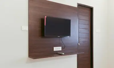 a flat screen tv on a wooden wall at Treebo Hi Line Apartments Kalapatti in Coimbatore