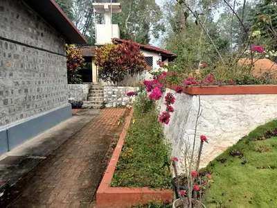 a garden with pink flowers next to a wall at Coorg Kolamotte in Gonikoppal