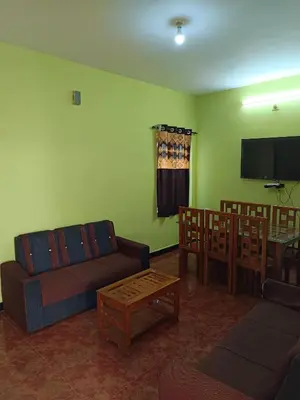 a living room with a couch and chairs and a flat screen tv at smile stone individual cottage in Ooty