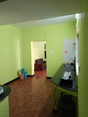 a room with green walls and a kitchen with a counter at smile stone individual cottage in Ooty