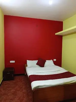 a bed in a room with a red wall at smile stone individual cottage in Ooty
