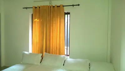 a bed with white pillows in front of a window at Siva Inn in Guruvāyūr