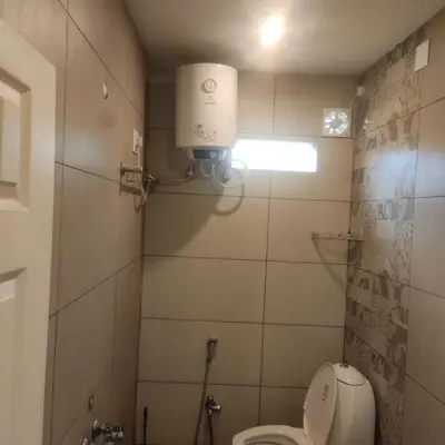 a bathroom with a toilet and a light on the wall at Snowdrops Ooty in Ooty