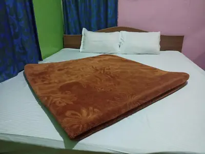 a bed with a brown blanket on top of it at Hill Inn Rooms an HomeStay in Ooty