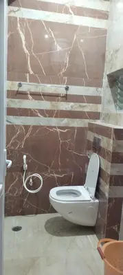 a bathroom with a white toilet in a brick wall at Hill Inn Rooms an HomeStay in Ooty