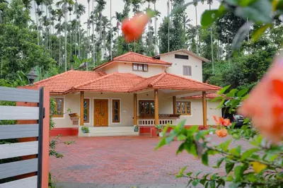 a small yellow house with a red roof at Nandanam Villa in Kaniyāmbetta