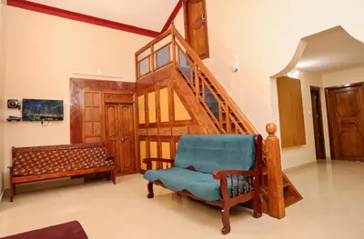 a living room with a staircase and a blue chair at Nandanam Villa in Kaniyāmbetta